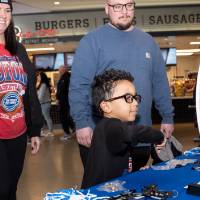 Young boy spins wheel at merch table while two adults watch